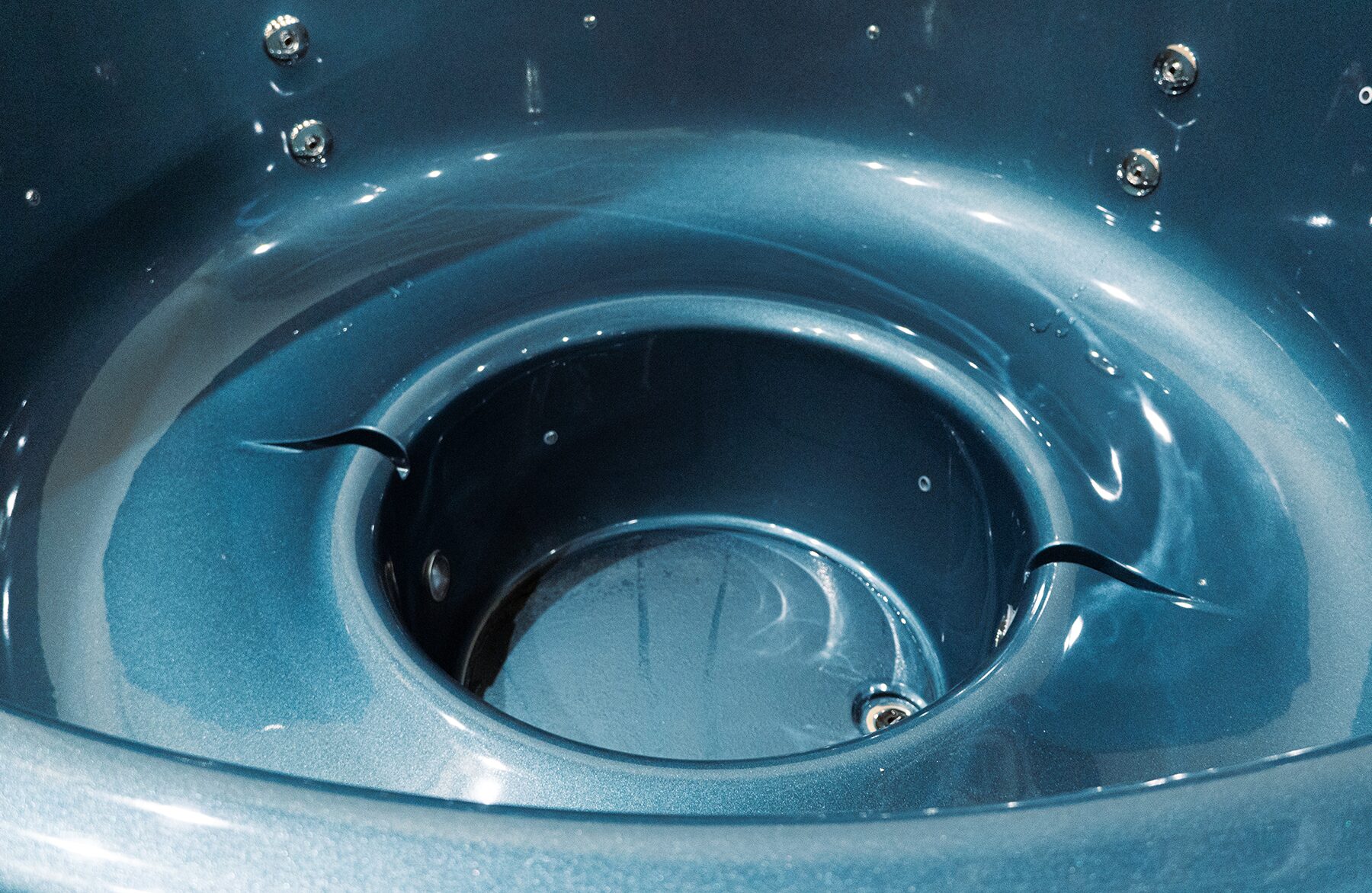 Close-up view of the blue interior tub of the Makoya Spa hot tub LUNA, featuring an ergonomic seating shape, integrated jets and a water drain.