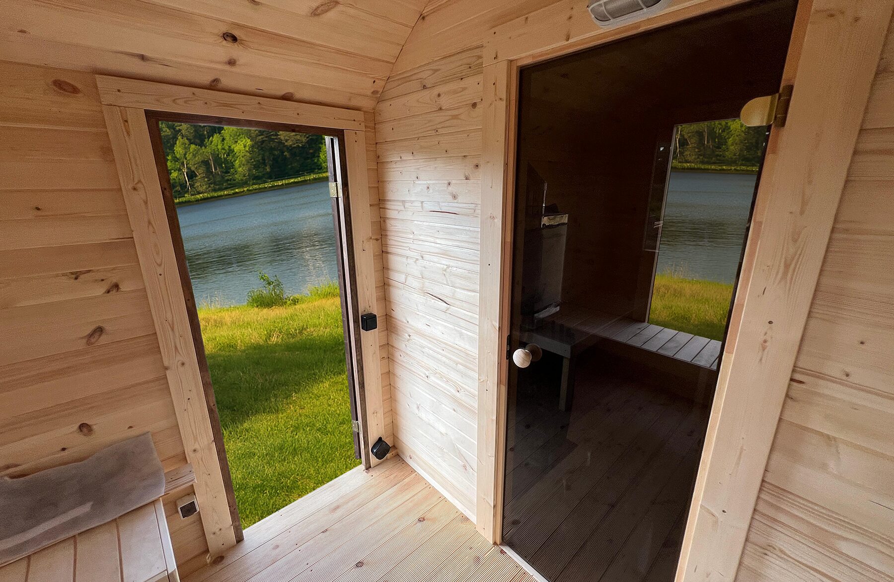 Interior view of the Makoya Spa sauna CERES featuring light wooden cladding, an integrated bench and glass door.