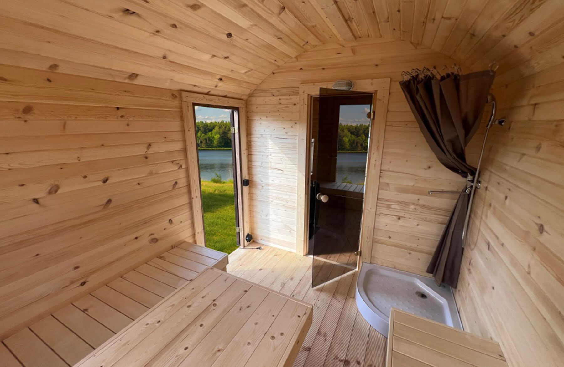 Interior view of the Makoya Spa sauna CERES featuring light wooden cladding, an integrated bench, a shower and a glass door.