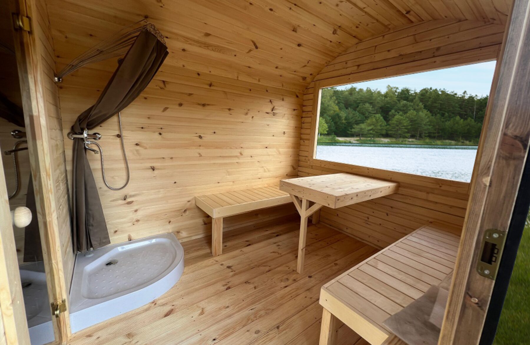 Interior view of the Makoya Spa sauna CERES featuring light wooden cladding, an integrated bench, a shower and a glass door.