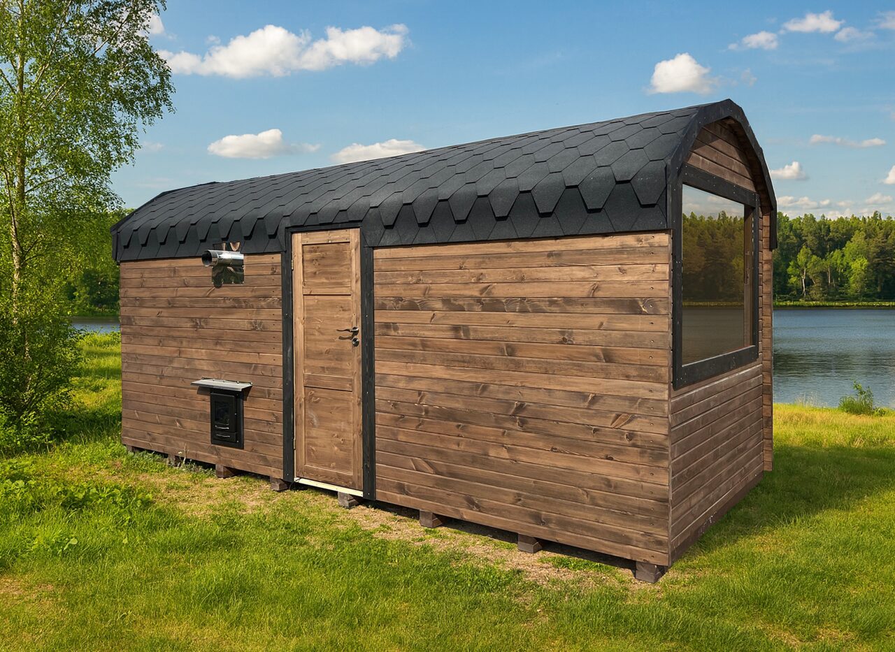 Makoya Spa sauna CERES set on a meadow, surrounded by bushes and trees, with a lake and blue sky visible in the background.