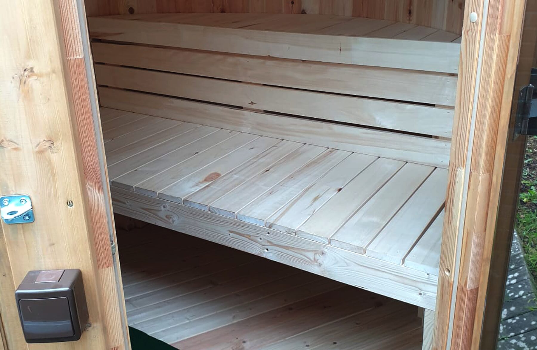 Interior view of the sauna VESTA by Makoya Spa featuring light wooden benches on two levels, visible natural wood grain, solid construction and a warm wooden finish in a compact sauna space