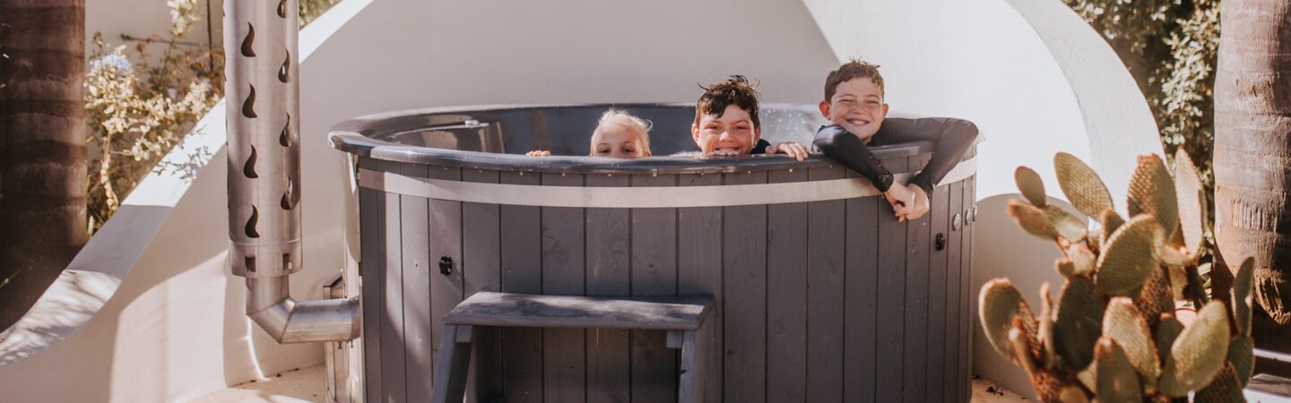 Happy kids playing in a wood-fired hot tub by Makoya Spa.